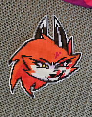 a photo of a crossstich of the head of a anthro fox lady smiling threateningly at the viewer with blood splattered across her face